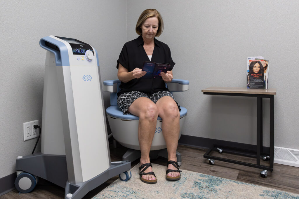 A woman is sitting on the Emsella chair for urinary incontinence treatment