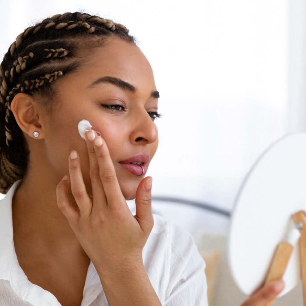 Woman's face as she applies some kind of cream to help with acne after having one of her Facials Near Cedar Falls